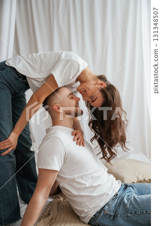 Woman is standing above man, willing to kiss. Young couple are together at home 131348507