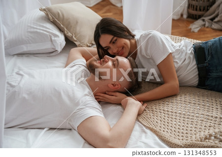 On the bed, lying down and smiling. Young couple are together at home On the bed, lying down and smiling. Young couple are together at home 131348553