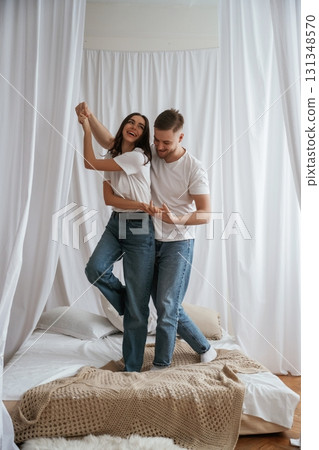 Standing and playing on the bed. Young couple are together at home Standing and playing on the bed. Young couple are together at home 131348570