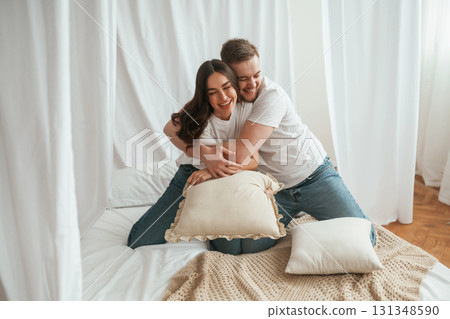 Soft pillows are in hands, playing. Young couple are together at home Soft pillows are in hands, playing. Young couple are together at home 131348590