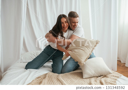 Soft pillows are in hands, playing. Young couple are together at home Soft pillows are in hands, playing. Young couple are together at home 131348592