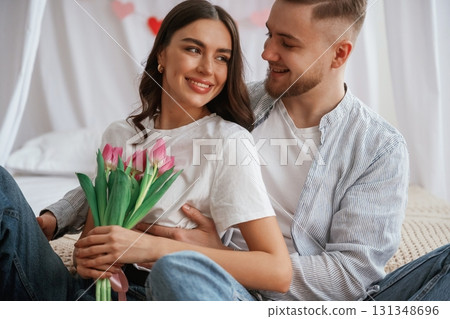 With beautiful flowers in hands. Young couple are together at home 131348696