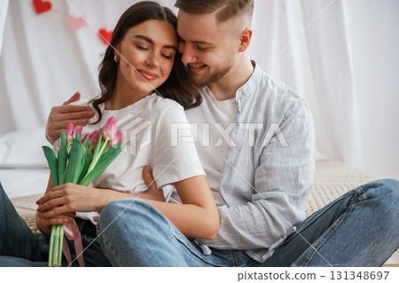 With beautiful flowers in hands. Young couple are together at home 131348697