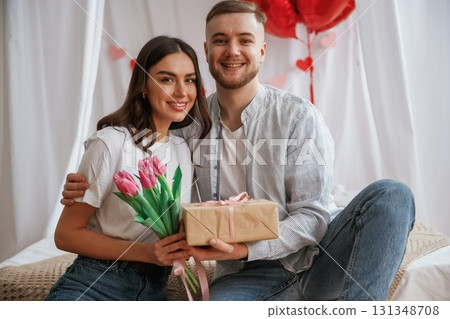 Gift box in hands, celebrating holiday. Young couple are together at home Gift box in hands, celebrating holiday. Young couple are together at home 131348708