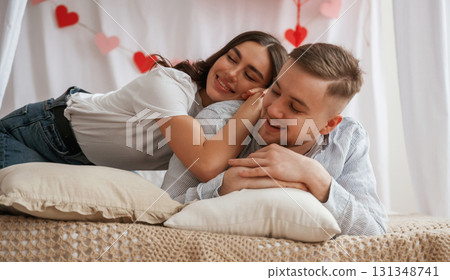 Background with red festive decorations for Valentine's day. Young couple are together at home Background with red festive decorations for Valentine's day. Young couple are together at home 131348741