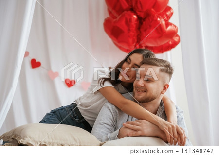 Bunch of heart shaped balloons, celebrating. Young couple are together at home Bunch of heart shaped balloons, celebrating. Young couple are together at home 131348742
