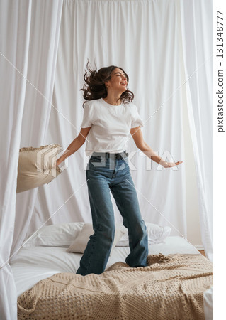 Jumping with pillow. Young beautiful woman is at home on the bed Jumping with pillow. Young beautiful woman is at home on the bed 131348777