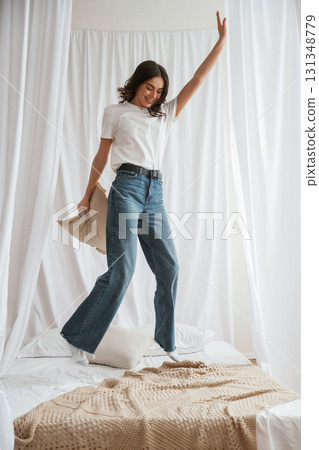 Having fun, jumping. Young beautiful woman is at home on the bed 131348779