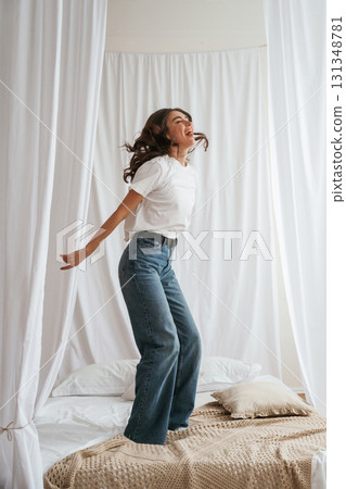 Having fun, jumping. Young beautiful woman is at home on the bed 131348781