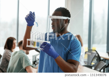 Black guy is in the protective mask. Group of doctors are together indoors Black guy is in the protective mask. Group of doctors are together indoors 131349076