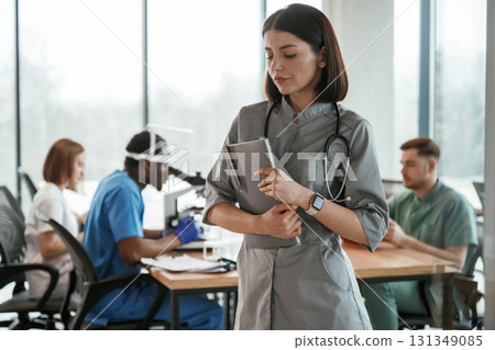 Confident woman is holding documents. Group of doctors are together indoors 131349085