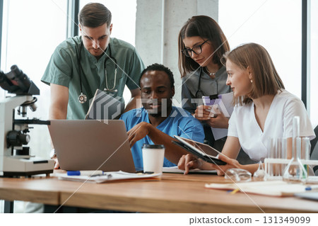 Reading information from laptop. Group of doctors are together indoors Reading information from laptop. Group of doctors are together indoors 131349099