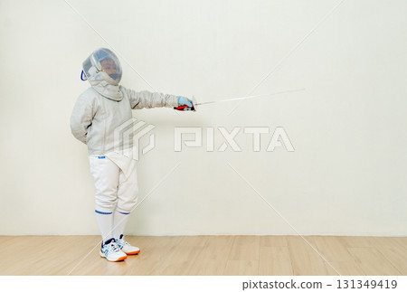 Asian boy with fencing sport uniform point epee to his front direction to act of practice for the competion. 131349419