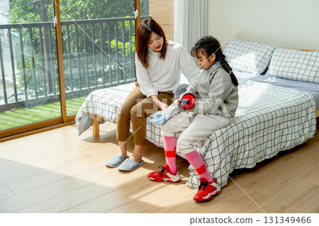 Asian mother sit near her child and help to wear uniform of fencing sport in bedroom with soft morning light and happiness. 131349466