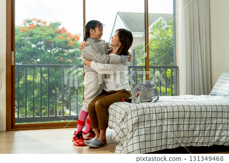 Asian mother sit on bed and hug together with her daughter during practice fencing sport in bedroom with soft morning light and happiness. 131349468