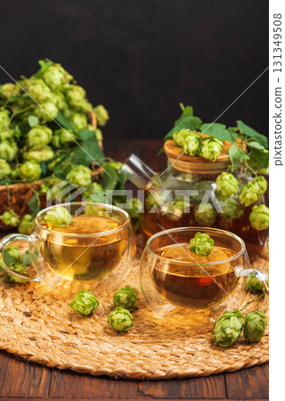Hop Tea with Fresh Hops in Glass Cups and Teapot on Rustic Background 131349508