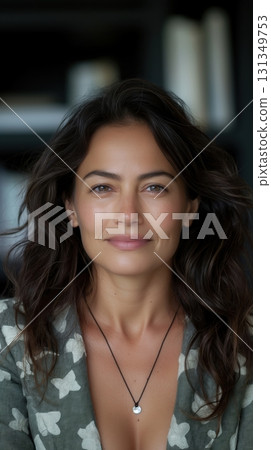 A woman with long brown hair and a necklace is smiling 131349753