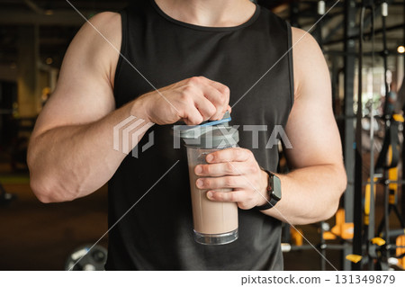 Portrait of young bodybuilder and sporty man with protein shake while working out at gym or fitness center. Health care and workout. 131349879