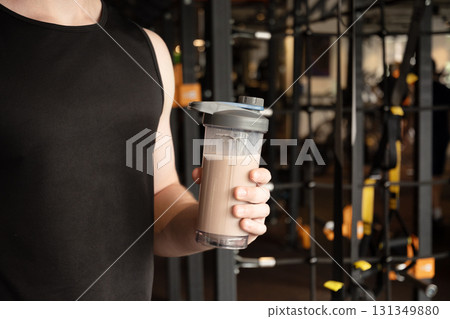 Protein shaker in man hand at gym or fitness center. Health care and workout. Close up. 131349880