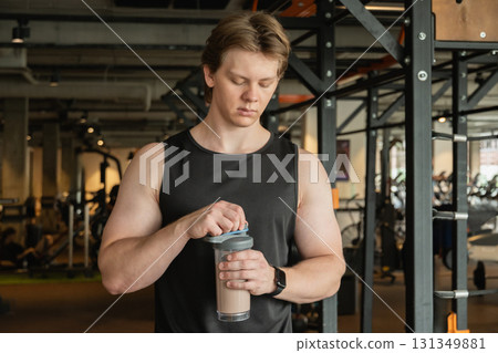 Bodybuilder and sporty man with protein shaker at gym or fitness center. Health care and workout. 131349881
