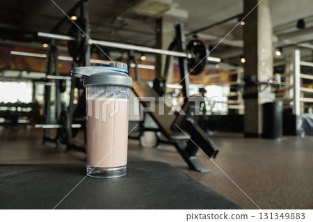 Protein shake in bottle at gym. Fitness enthusiasm and post-workout routine. Healthy lifestyle and recovery after training. Close up. 131349883