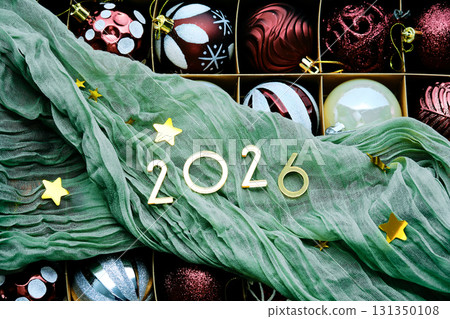 New Year's background with a box of Christmas tree toys and green drapery. New Year's background with a box of Christmas tree toys and green drapery. 131350108