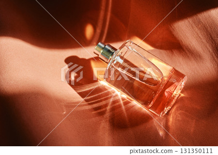 A pink perfume bottle on a soft reddish background. 131350111