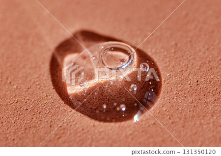 A drop of cosmetic product on a terracotta background. A drop of cosmetic product on a terracotta background. 131350120