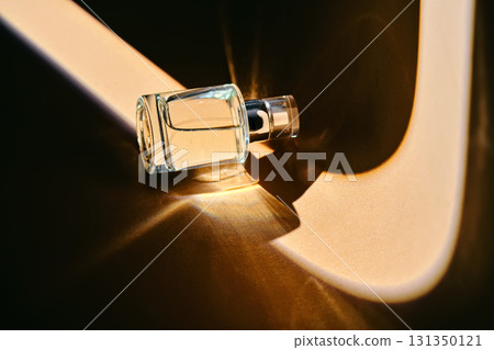 A spray bottle with perfume on a beige background with a light strip. A spray bottle with perfume on a beige background with a light strip. 131350121