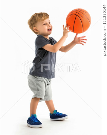 A young boy is holding a basketball and smiling 131350144