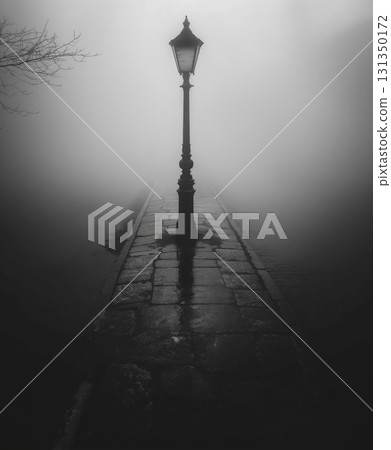 A street lamp is lit up in the fog 131350172