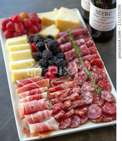 A white plate with a variety of meats and cheeses, including ham, cheese A white plate with a variety of meats and cheeses, including ham, cheese 131350200
