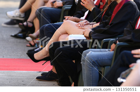 Stylish female graduate wearing high heels sits among students showing elegant legs during ceremony Stylish female graduate wearing high heels sits among students showing elegant legs during ceremony 131350551