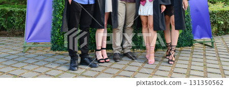 Portraits of student at graduation ceremony with group and family posing outdoors in celebration 131350562