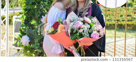 Portraits of student at graduation ceremony with group and family posing outdoors in celebration Portraits of student at graduation ceremony with group and family posing outdoors in celebration 131350567