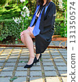 Elegant female student poses proudly in graduation outfit showing beautiful legs and high heels 131350574