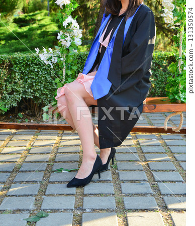 Elegant female student poses proudly in graduation outfit showing beautiful legs and high heels Elegant female student poses proudly in graduation outfit showing beautiful legs and high heels 131350574