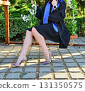 Elegant female student poses proudly in graduation outfit showing beautiful legs and high heels 131350575