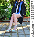Elegant female student poses proudly in graduation outfit showing beautiful legs and high heels 131350577