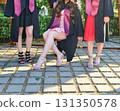 Elegant female student poses proudly in graduation outfit showing beautiful legs and high heels 131350578