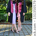 Elegant female student poses proudly in graduation outfit showing beautiful legs and high heels 131350579