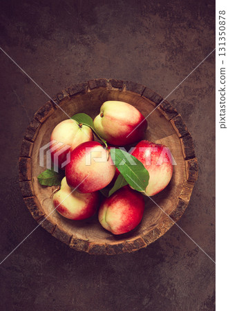 ripe nectarine, in a wooden plate, brown background, top view, no people, 131350878