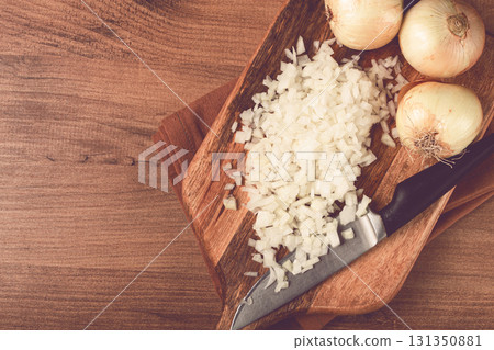 finely chopped onion on a chopping board with a knife, wooden table, top view, no people, finely chopped onion on a chopping board with a knife, wooden table, top view, no people, 131350881