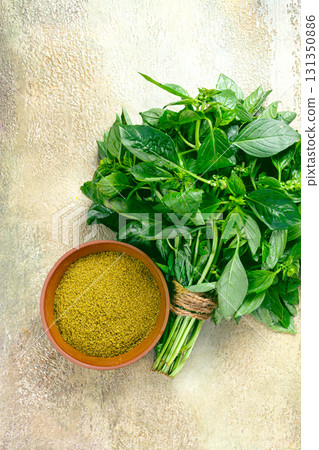 ground green basil, in a ceramic bowl, with a bouquet of fresh green basil, on the table, top view, no people, ground green basil, in a ceramic bowl, with a bouquet of fresh green basil, on the table, top view, no people, 131350886