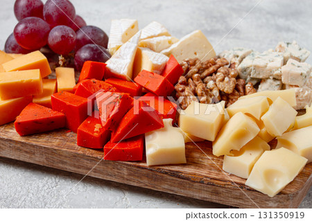 Assorted cheese on a wooden board, with grapes and walnuts, appetizer, no people. 131350919