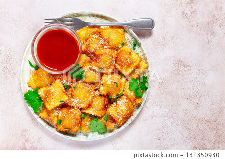 fried ravioli with parmesan cheese, served with red sauce and garnished with herbs, on a light background, no people, 131350930