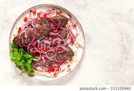 grilled kebabs topped with onions and pomegranate on a white plate in a bright kitchen setting grilled kebabs topped with onions and pomegranate on a white plate in a bright kitchen setting 131350940