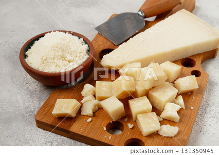 Freshly sliced and grated cheese, parmesan cheese, on a wooden chopping board, rustic style, no people 131350945