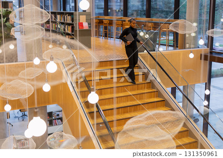 Student descending staircase in library 131350961
