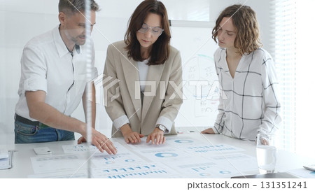 Professional colleagues reviewing financial reports, collaborating on strategic planning in contemporary workspace. Business people concept Professional colleagues reviewing financial reports, collaborating on strategic planning in contemporary workspace. Business people concept 131351241